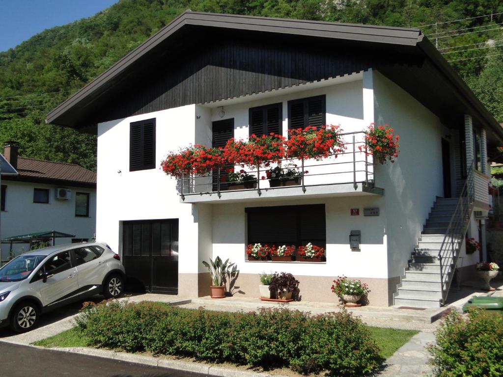 ein weißes Haus mit Blumen auf den Balkonen in der Unterkunft Apartma Jezero in Most na Soči