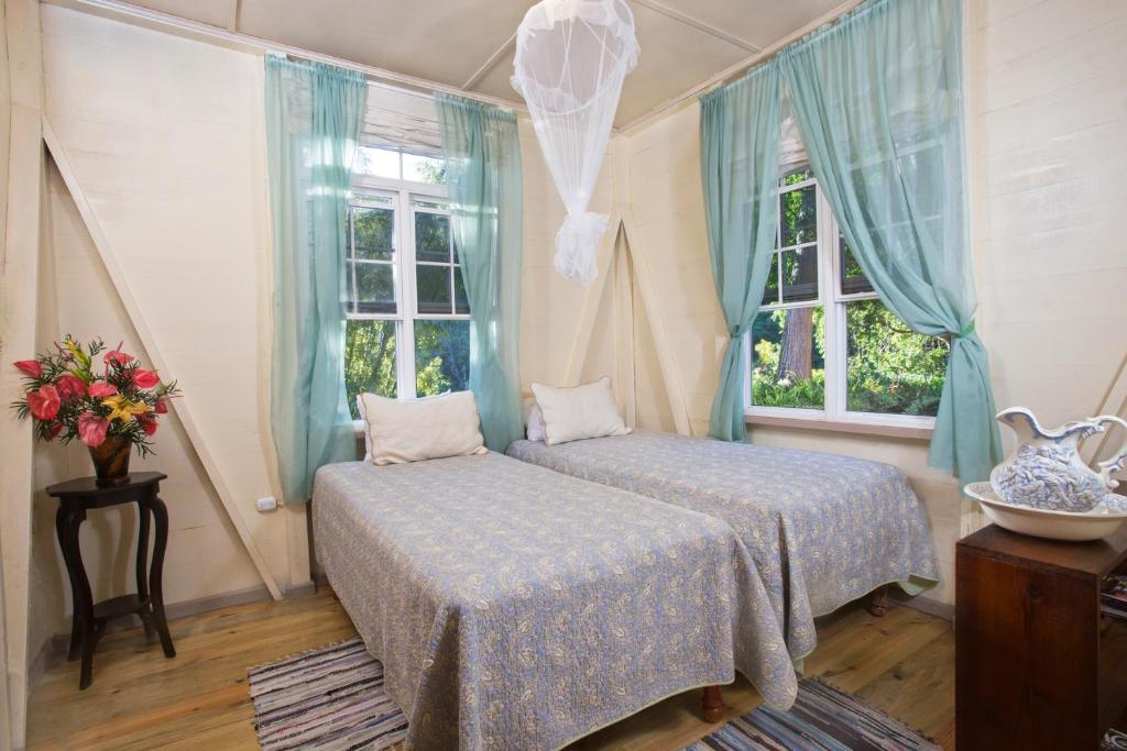 a bedroom with two beds and two windows at Barbecue Heritage Gardens Cottage - JM in Newcastle
