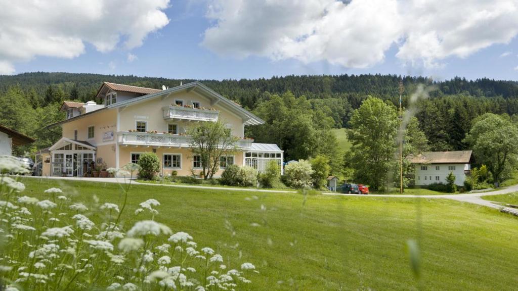a large house on a hill with a green field at Landgasthof Hotel Zum Hirschenstein, Pension Garni in Sankt Englmar