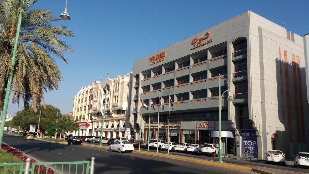 Top Hotel Apartments في العين: مبنى على شارع فيه سيارات تقف امامه