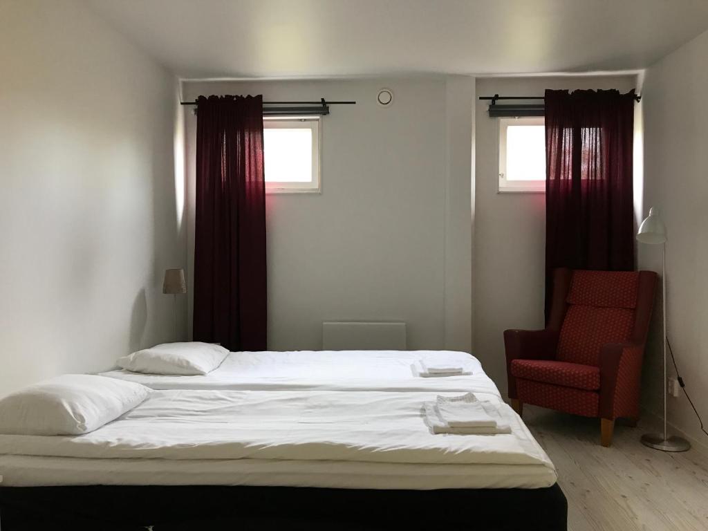 a bedroom with a bed and a red chair at Fjord Hostel Rooms in Lysekil