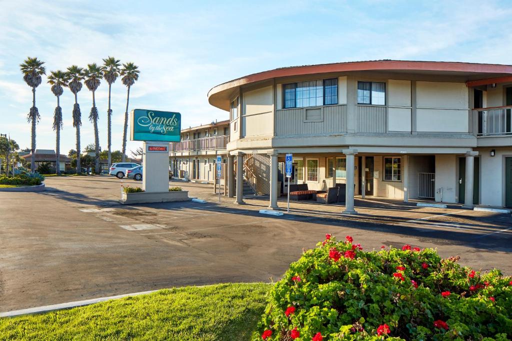 a sign in front of a building with palm trees at Sands by the Sea Motel in San Simeon