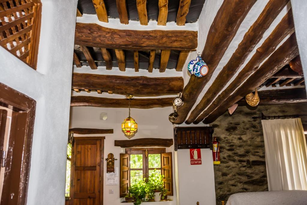 una sala de estar con techos de madera y vigas de madera. en Casa el Portón, en Bubión