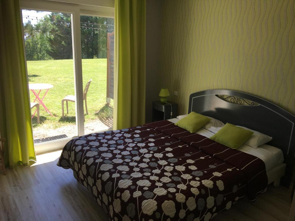 Schlafzimmer mit einem Bett und einer Glasschiebetür in der Unterkunft Logis Hotel La Bergerie in Saint-Pierre-Lafeuille