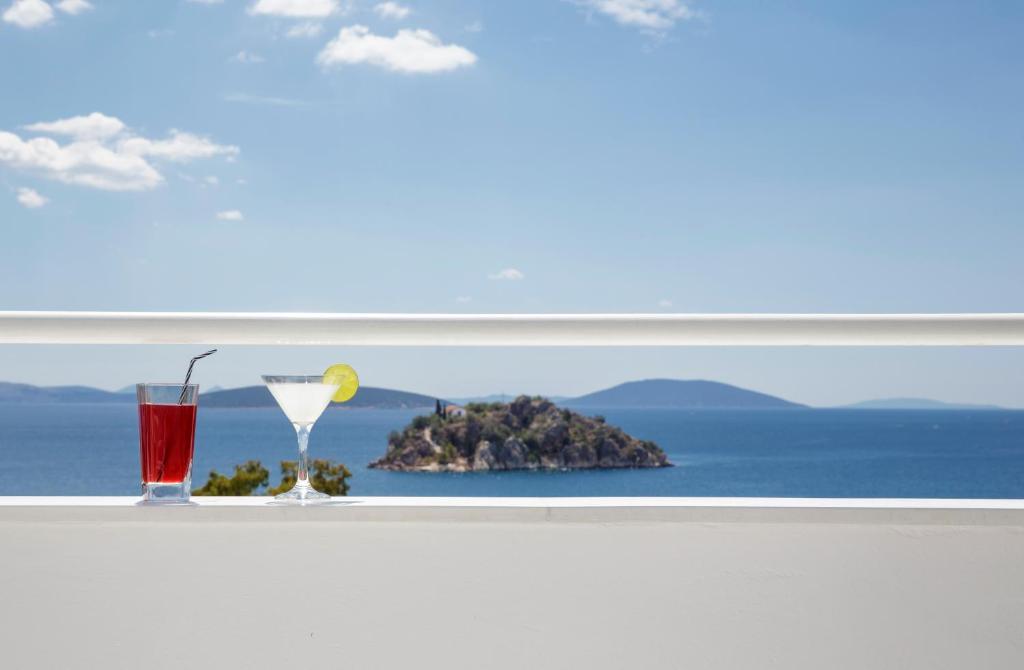 a window with two glasses and a view of the ocean at Asteria Hotel in Tolo