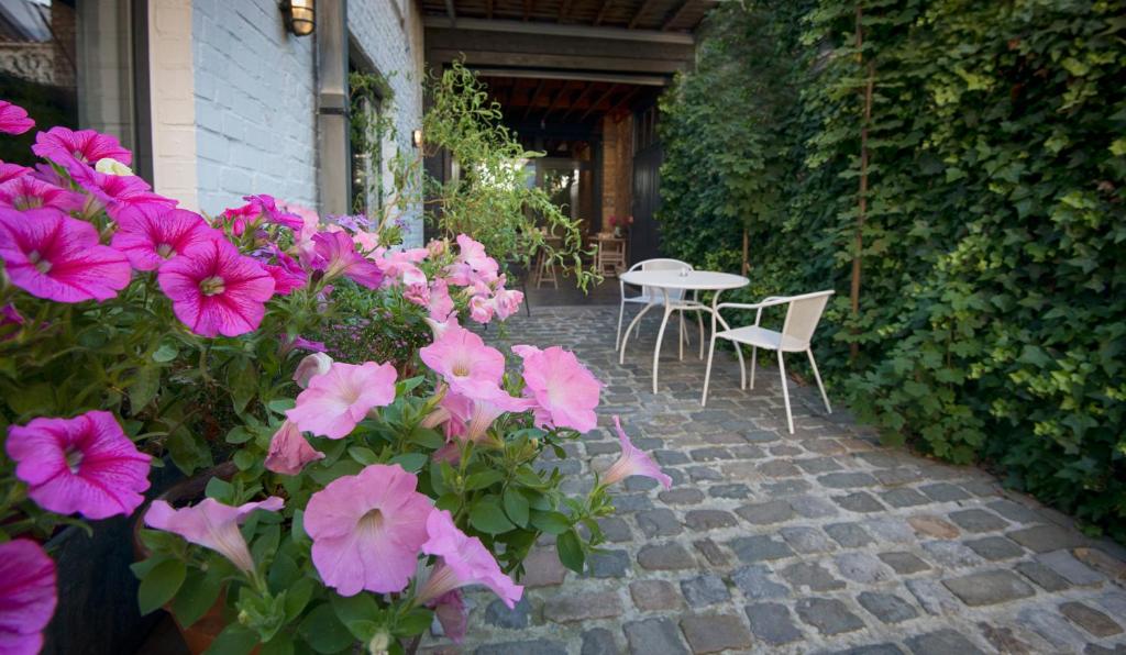 eine Terrasse mit rosa Blumen, einem Tisch und Stühlen in der Unterkunft Gastenkamers UitGaanSlapen in Nieuwpoort
