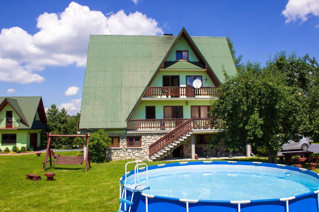 ein Haus mit einem Pool vor einem Haus in der Unterkunft Hacjenda - Apartamenty i Pokoje Gościnne in Czarna Góra