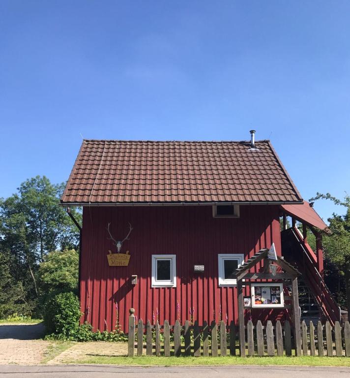 a red barn with a fence in front of it at Fischer Hütte in Sankt Andreasberg