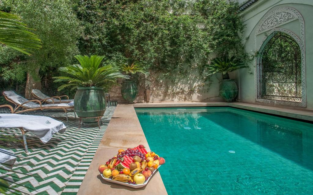 a bowl of fruit sitting next to a swimming pool at Riad & Spa Laurence Olivier in Marrakesh