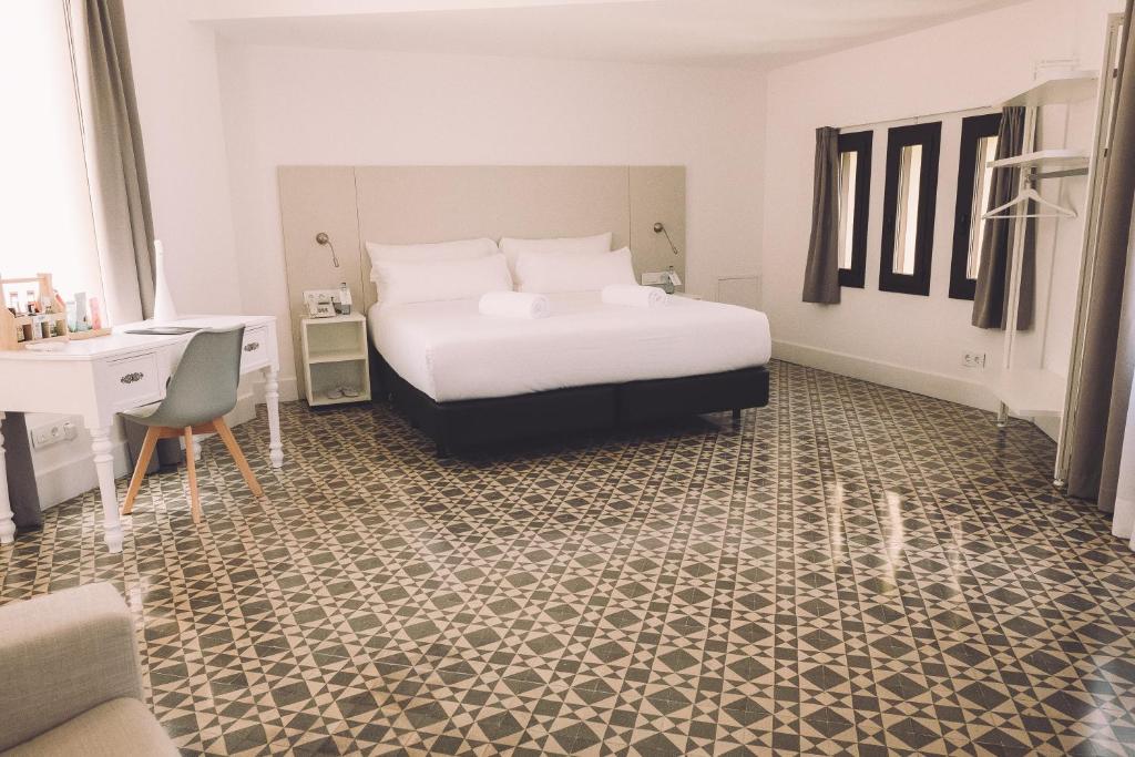 a bedroom with a bed and a desk and a chair at Hotelet Casa Padró in Manresa