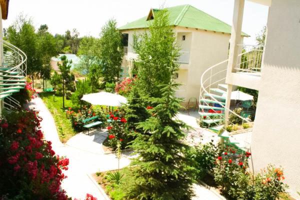 einen Garten mit einem Baum und Blumen und einem Gebäude in der Unterkunft Evita Hotel in Dolinka