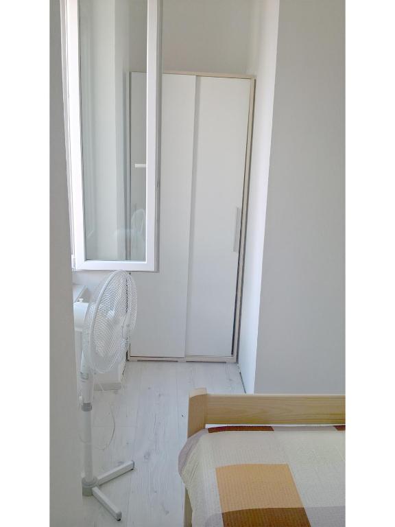 a white room with a bed and a fan at San Eleuterio Guesthouse in Poreč