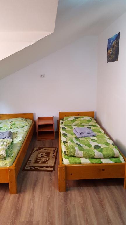 two beds sitting in a room with wooden floors at Casa Borcean in Sasca Montană