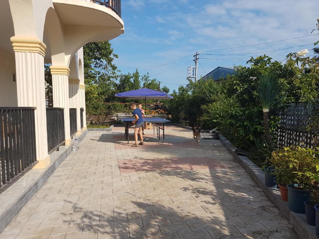 a woman standing at a table with a purple umbrella at Talo's Guest House in Makhinjauri