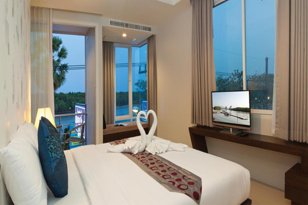 a bedroom with a bed and a tv and windows at Krabi River View Hotel in Krabi town