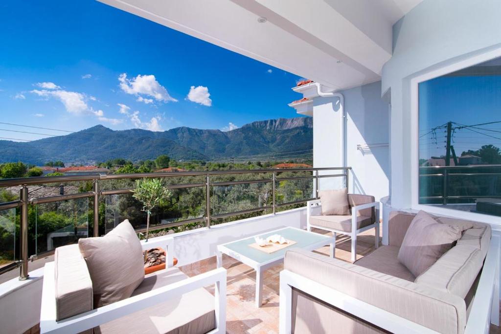 a balcony with white furniture and a view of mountains at Olive Garden Villas and Apartments in Chrysi Ammoudia