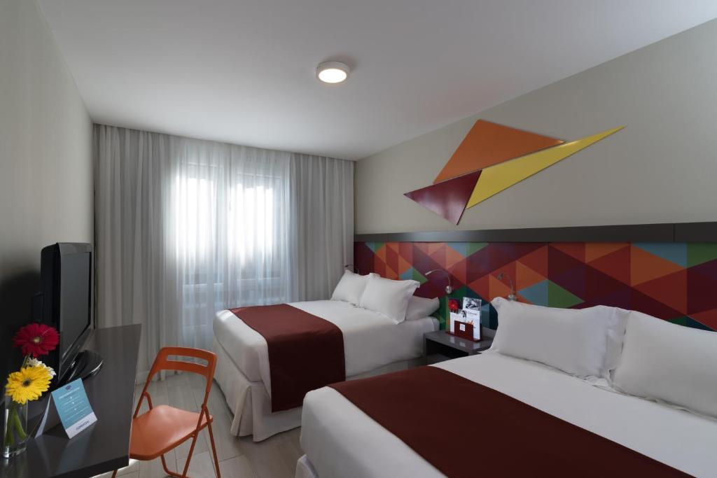 Habitación de hotel con 2 camas y una pared colorida. en Novus Plaza Hodelpa en Santo Domingo