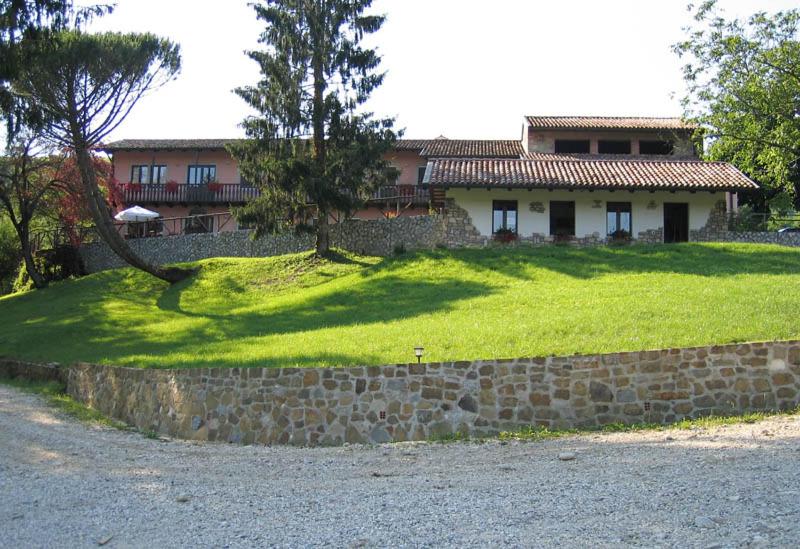 una casa con un ampio cortile con un muro di pietra di Tenuta Valdomini ad Attimis
