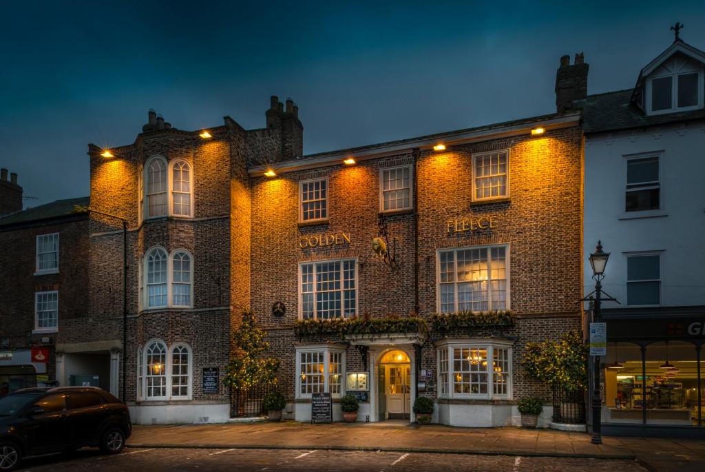 un gran edificio de ladrillo con luces. en The Golden Fleece Hotel, Thirsk, North Yorkshire, en Thirsk