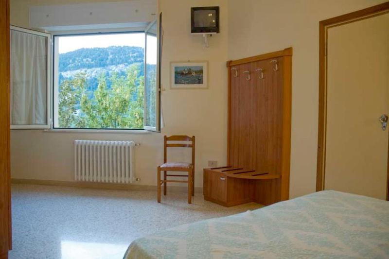 a bedroom with a bed and a chair and a window at Hotel Viola in Caramanico Terme