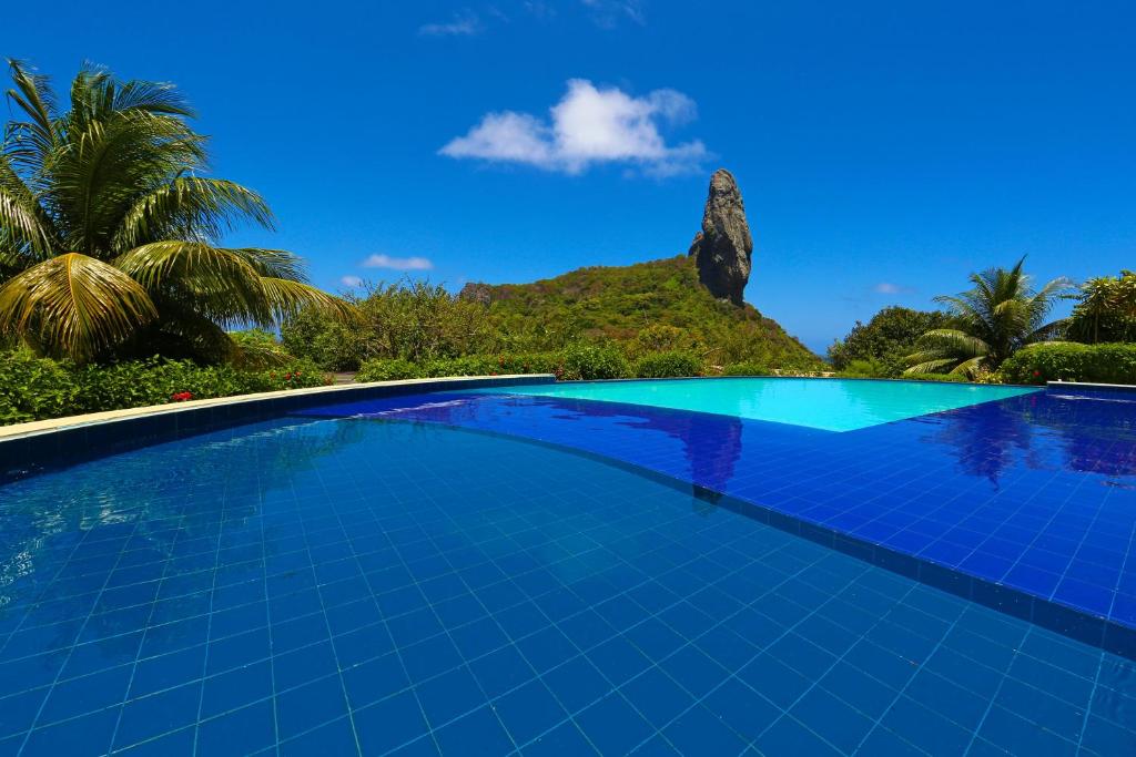 a swimming pool with a mountain in the background at Pousada Zé Maria in Fernando de Noronha