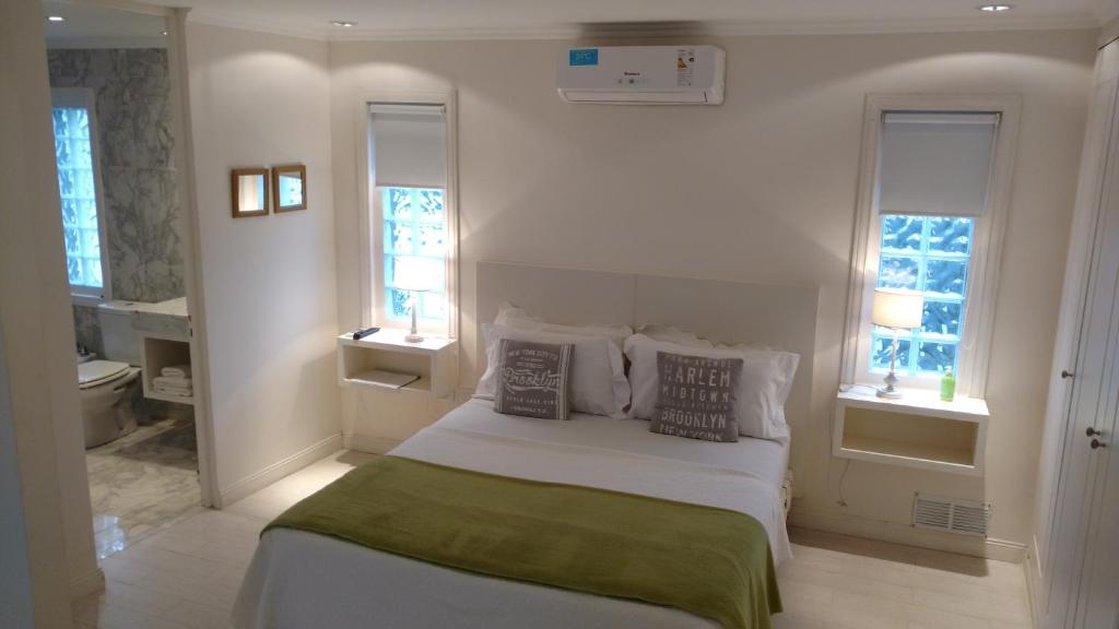 a white bedroom with a bed and two windows at Little Posadas in Concepción del Uruguay