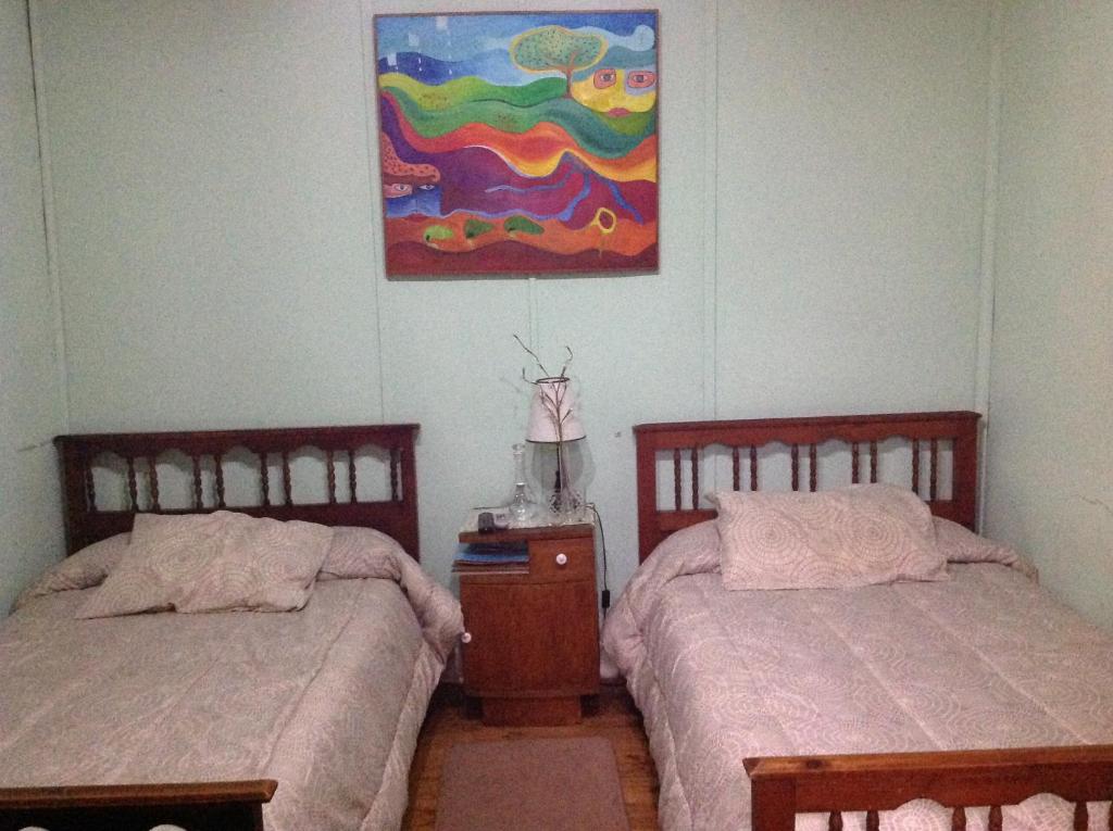 2 camas en un dormitorio con una pintura en la pared en Hostal Renoir, en San Fernando