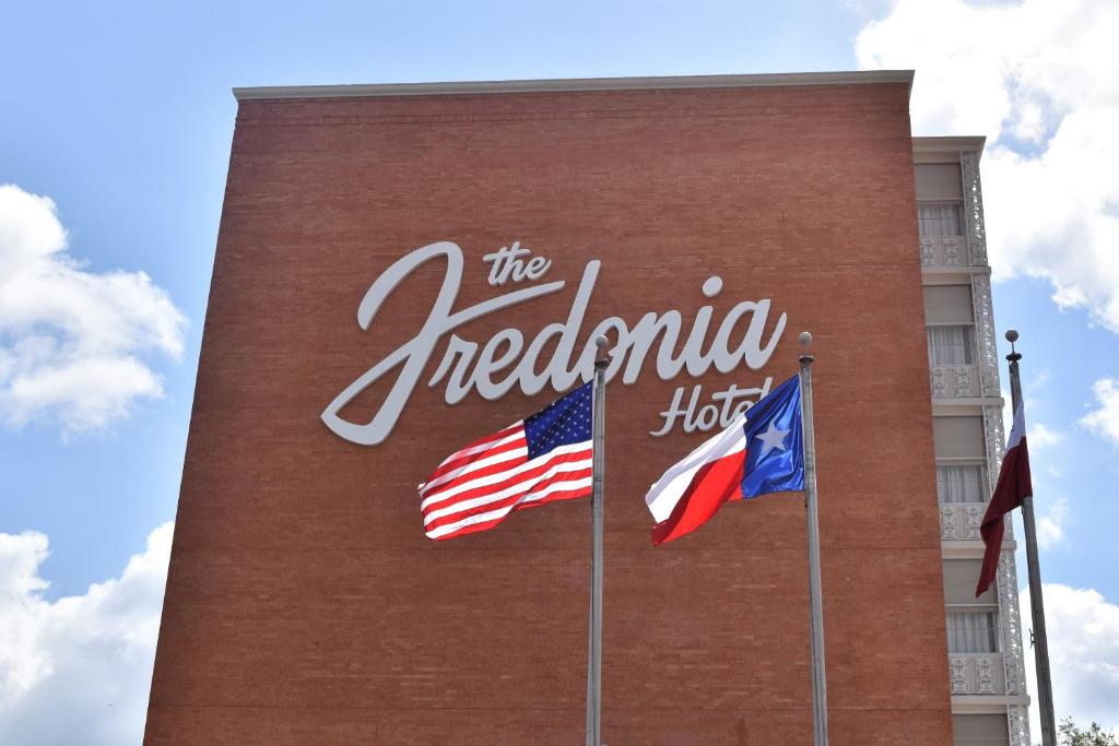 un cartello hotel sul lato di un edificio con due bandiere di The Fredonia Hotel a Nacogdoches