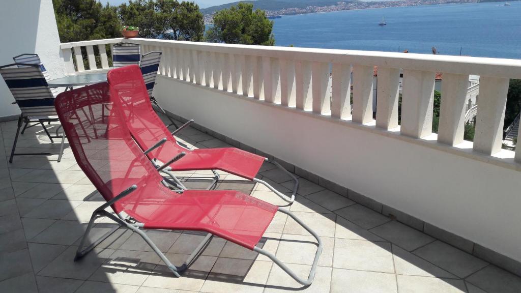 um par de cadeiras vermelhas sentadas numa varanda em Apartment "Marin" em Trogir