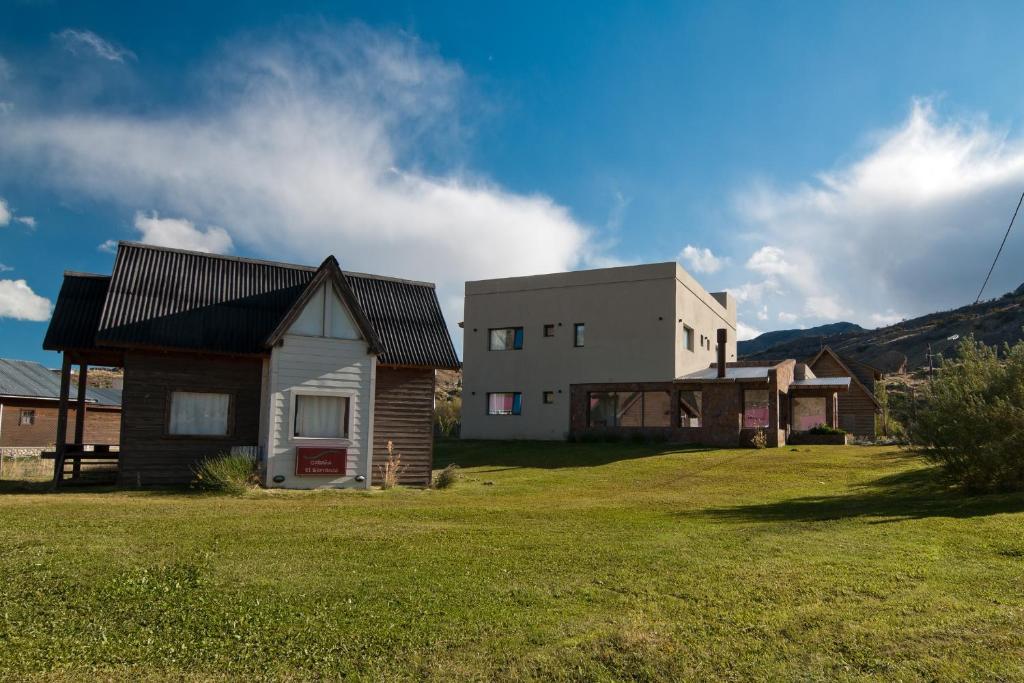 una casa en un campo de hierba al lado de un edificio en Posada y Cabañas El Barranco en El Chaltén