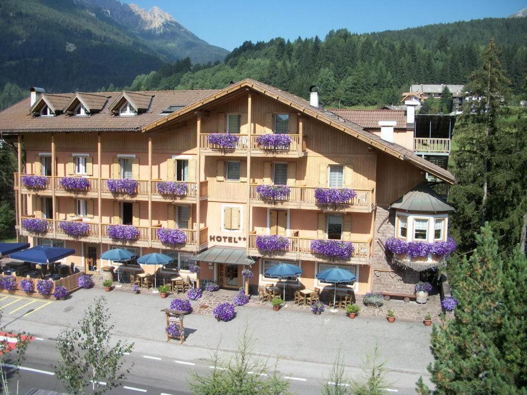 ein großes Hotel mit lila Blumen auf den Balkonen in der Unterkunft Hotel Vallechiara in Moena