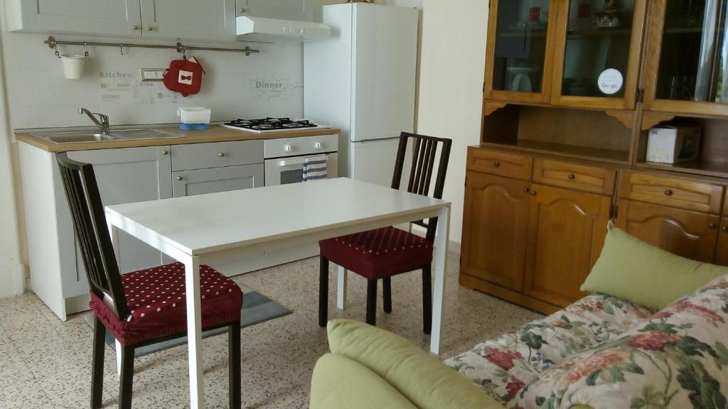 cocina con mesa blanca, 2 sillas y sofá en B&B Le Volte, en Sarno