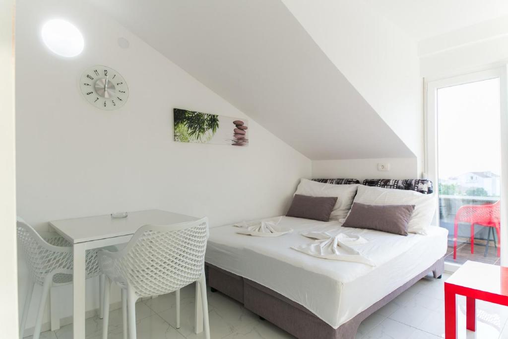 ein weißes Schlafzimmer mit einem Bett, einem Tisch und Stühlen in der Unterkunft Villa JASMINA in Novalja