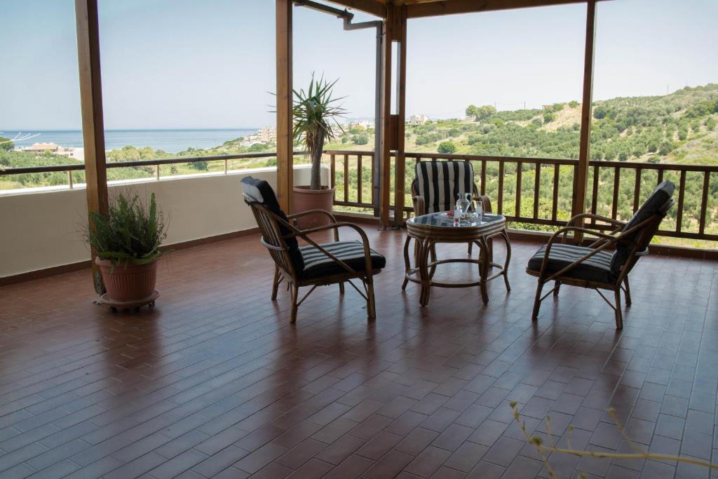 a room with chairs and a table and a balcony at Alexandra Villa Stalos in Stalos