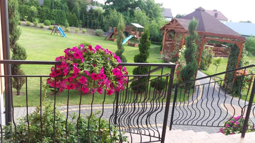 una valla de hierro forjado con una cesta colgante de flores rosas en Hotel Restauracja Rywa Verci en Stopnica