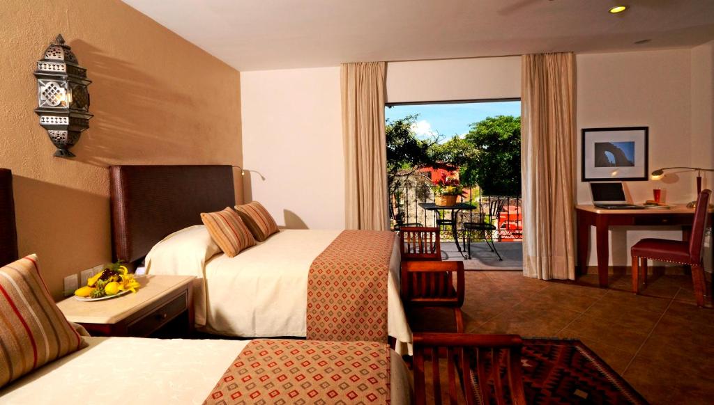 a hotel room with two beds and a balcony at Hotel & Spa Hacienda de Cortés in Cuernavaca