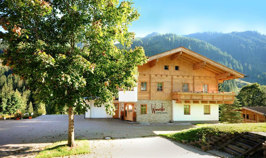 une maison avec un arbre en face dans l'établissement Appartement Wimreiter, à Saalbach-Hinterglemm