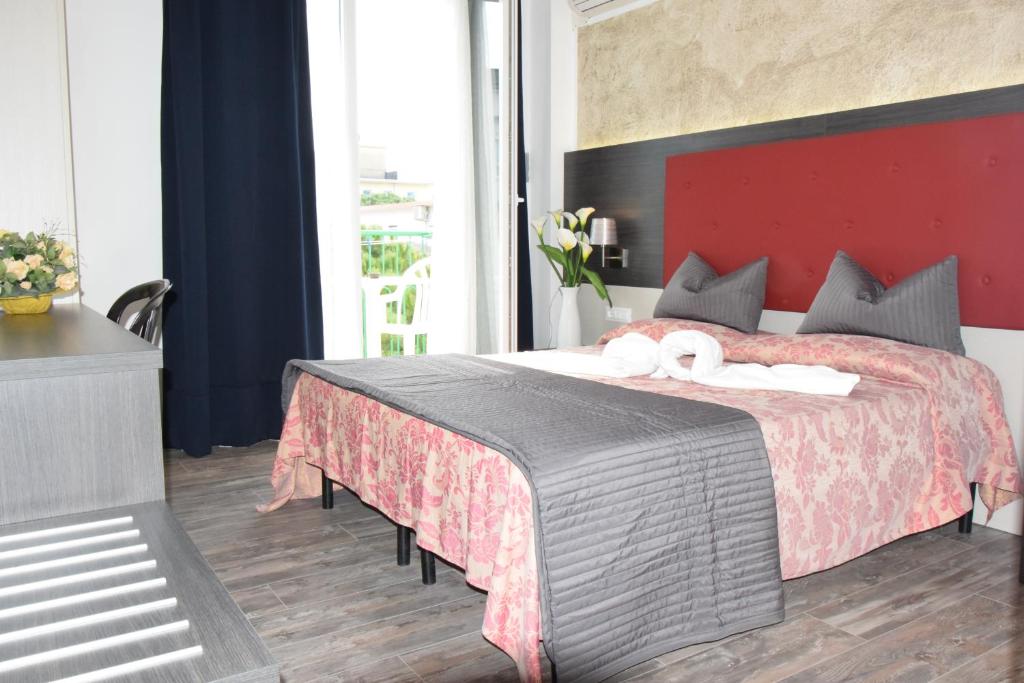 a bedroom with a large bed with a red headboard at Hotel Verdi in Lido di Jesolo