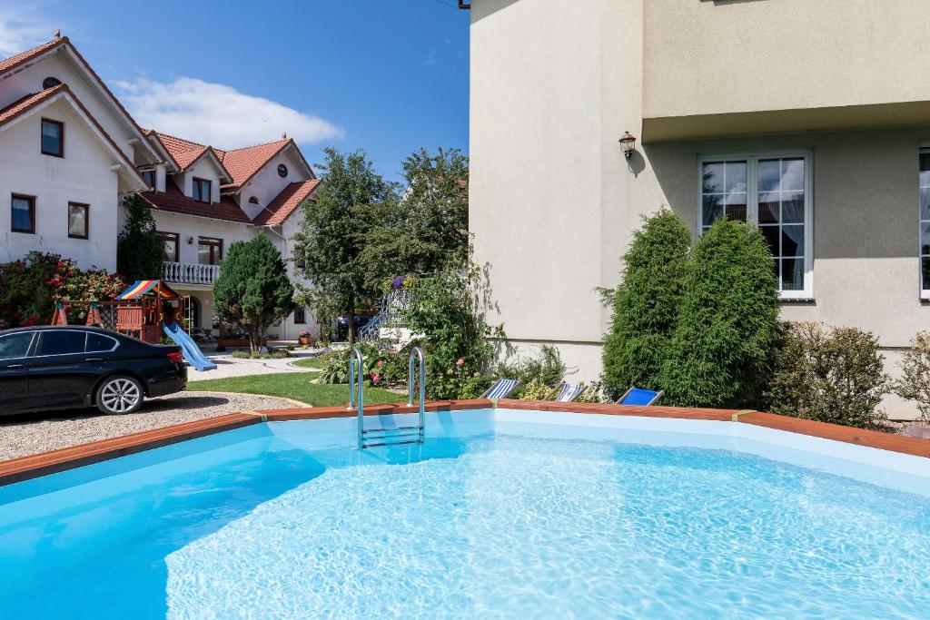 a large blue swimming pool in front of a house at Bałtyk Resort in Rewal