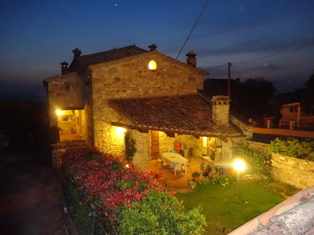 una casa de piedra con un patio con flores y luces en B&B Fonte Dei Billi, en Pennabilli