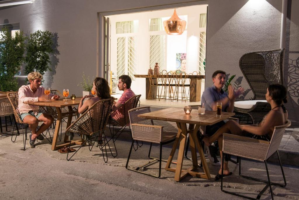 a group of people sitting at tables in a patio at Nyx Chic Manor in Chania