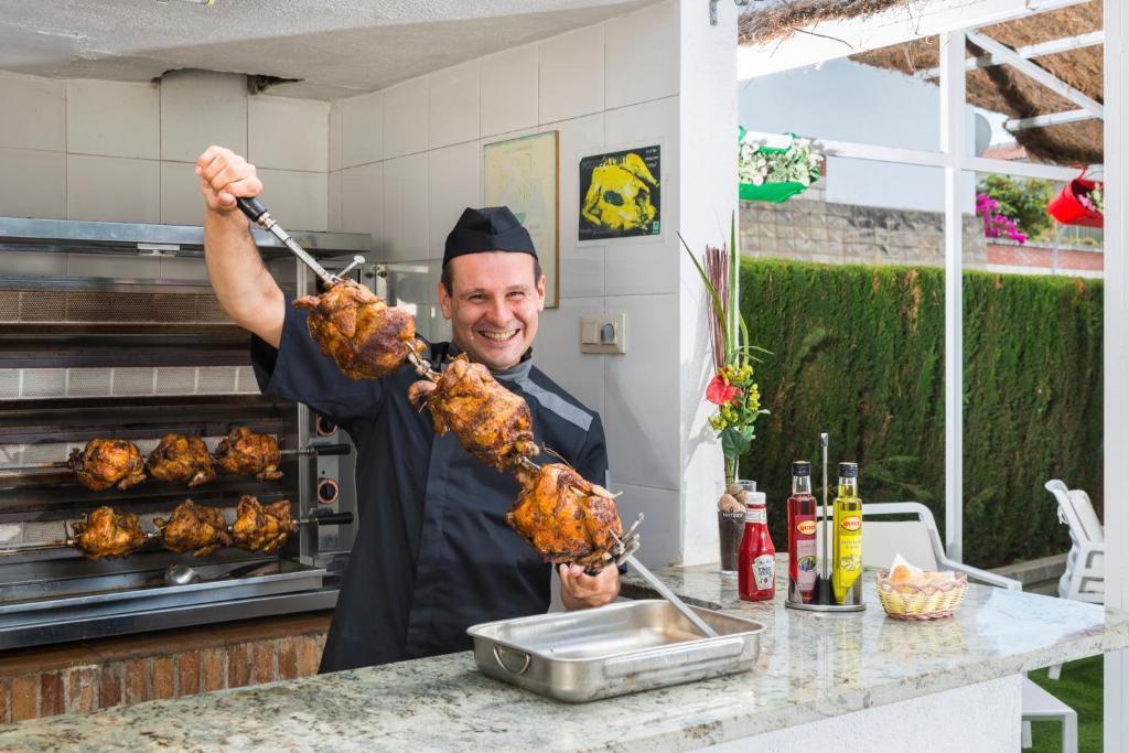 a man holding up a bunch of meat on tongs at Apartaments Els Llorers in Lloret de Mar