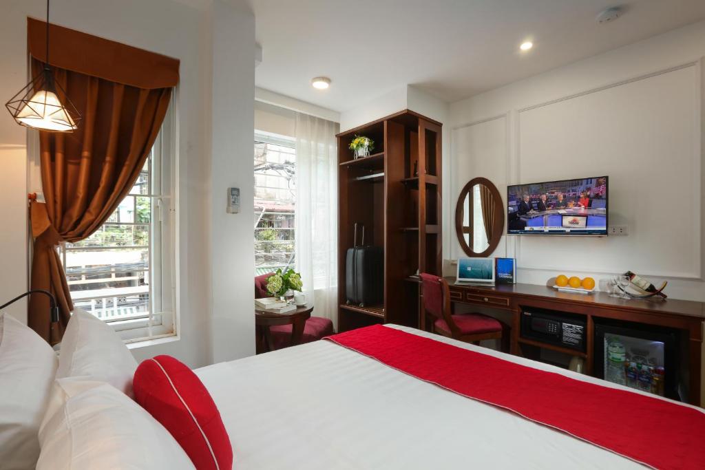 1 dormitorio con 1 cama y escritorio con TV en Hanoi La Vision Hotel, en Hanói