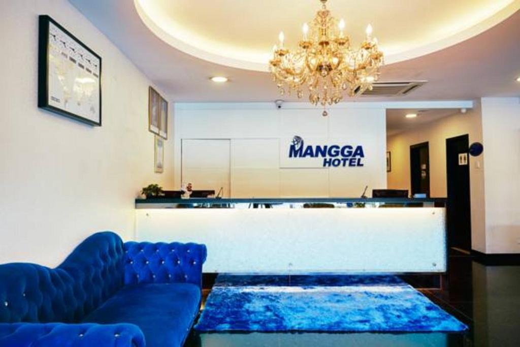 a waiting room with two blue couches and a chandelier at Mangga Boutique Hotel in Seri Kembangan