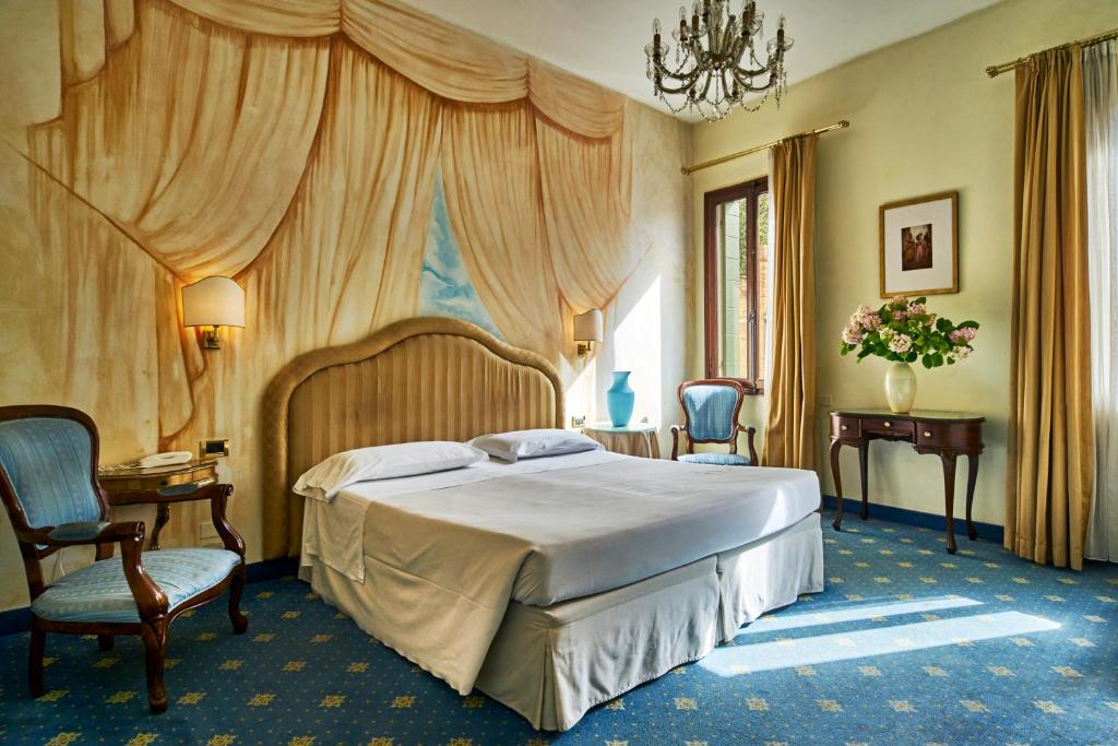 a bedroom with a large bed and two chairs at Hotel Gardena in Venice
