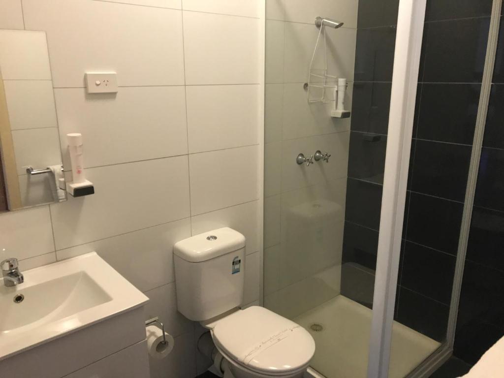 a bathroom with a toilet and a shower and a sink at The Wharf Hotel in Wynyard