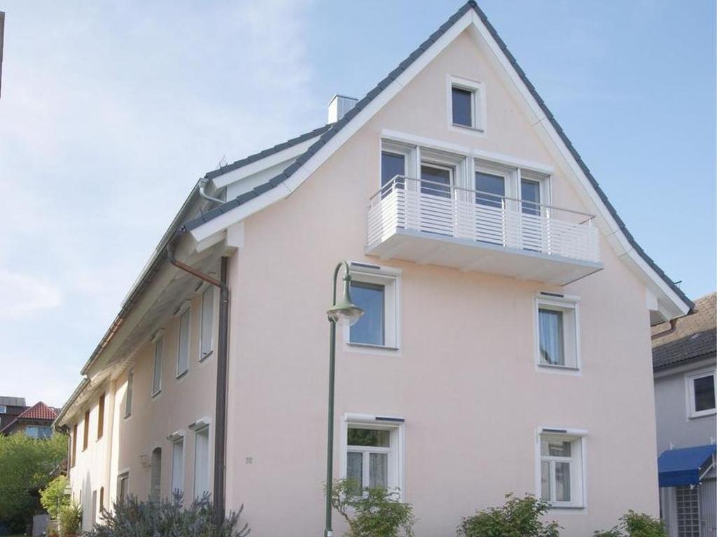 a white house with a balcony on top of it at Haus Rebstein in Immenstaad am Bodensee