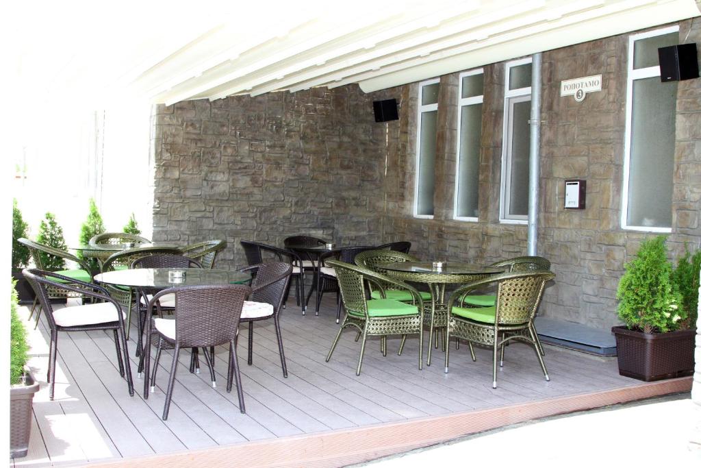 un patio al aire libre con mesas, sillas y una pared de ladrillo en Vlasta Family Hotel en Ravda
