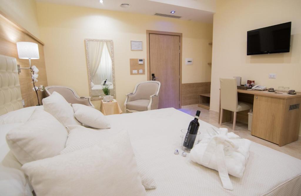 ローマにあるエスポジツィオーネ パレス ホテルの白いソファとデスクが備わるホテルルームです。