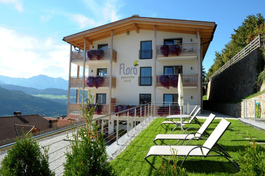 ein Gebäude auf dem Hügel mit Stühlen davor in der Unterkunft Panorama Hotel Flora in Villanders